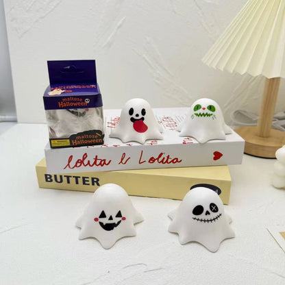 Four Halloween ghost squeeze toys in different face designs on a desk
